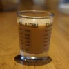 Glass measuring shot glass with milliliter markings filled with beverage