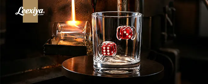 Custom whiskey glass embedded with red dice showcasing handcrafted glassware manufacturing for brands